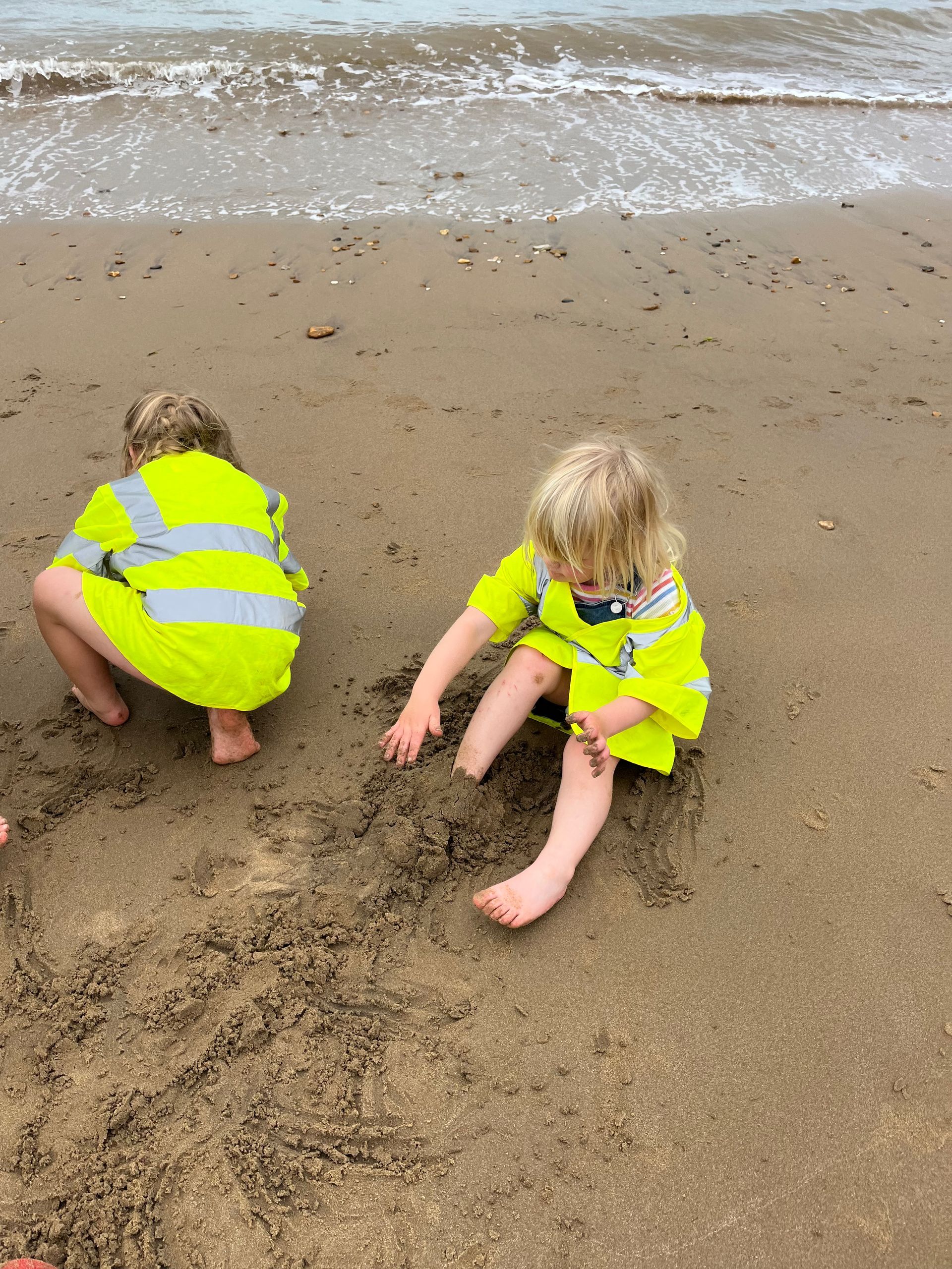 Two children are playing in the sand on the beach