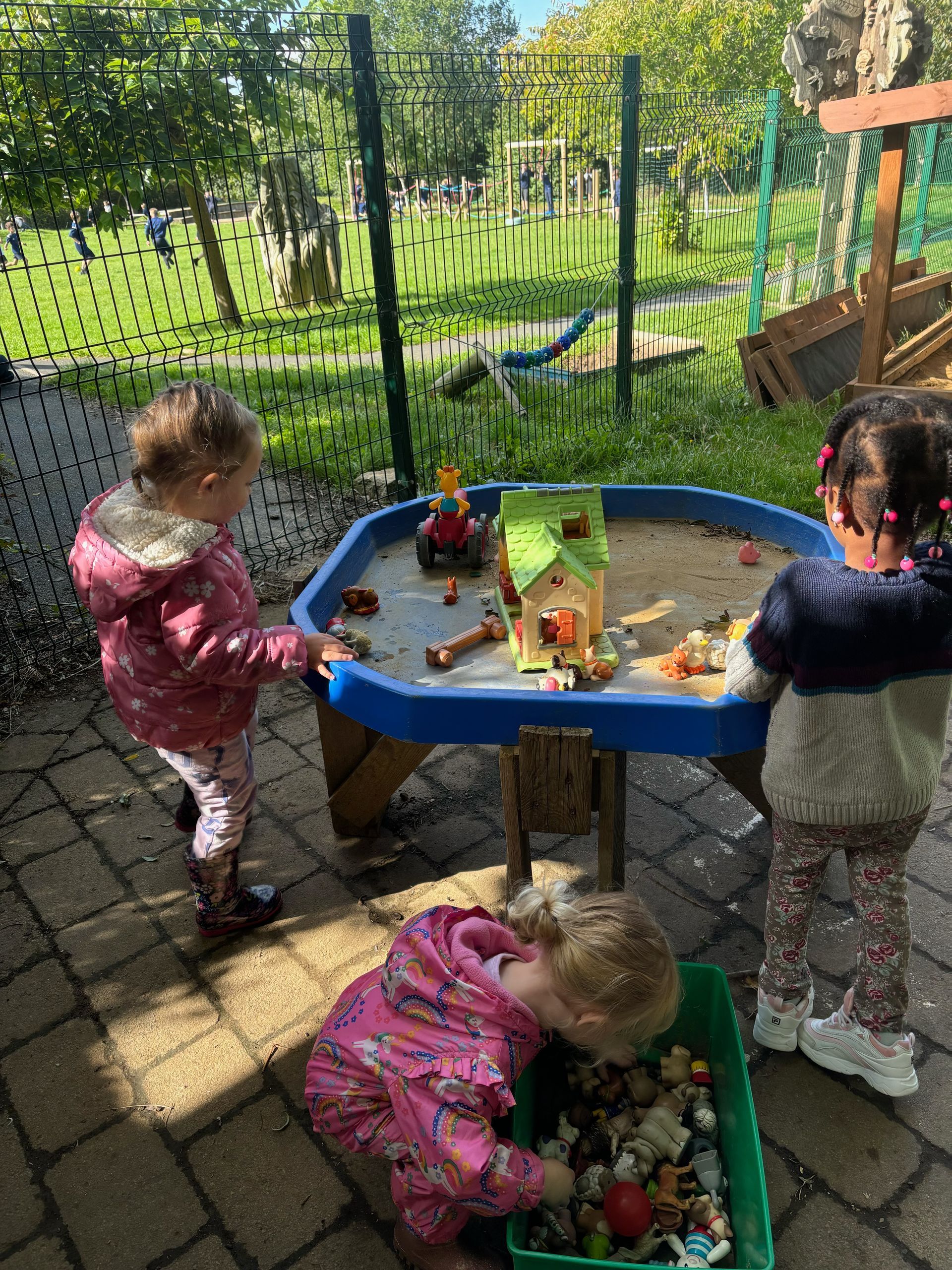 Two little girls are playing in a sandbox outside.