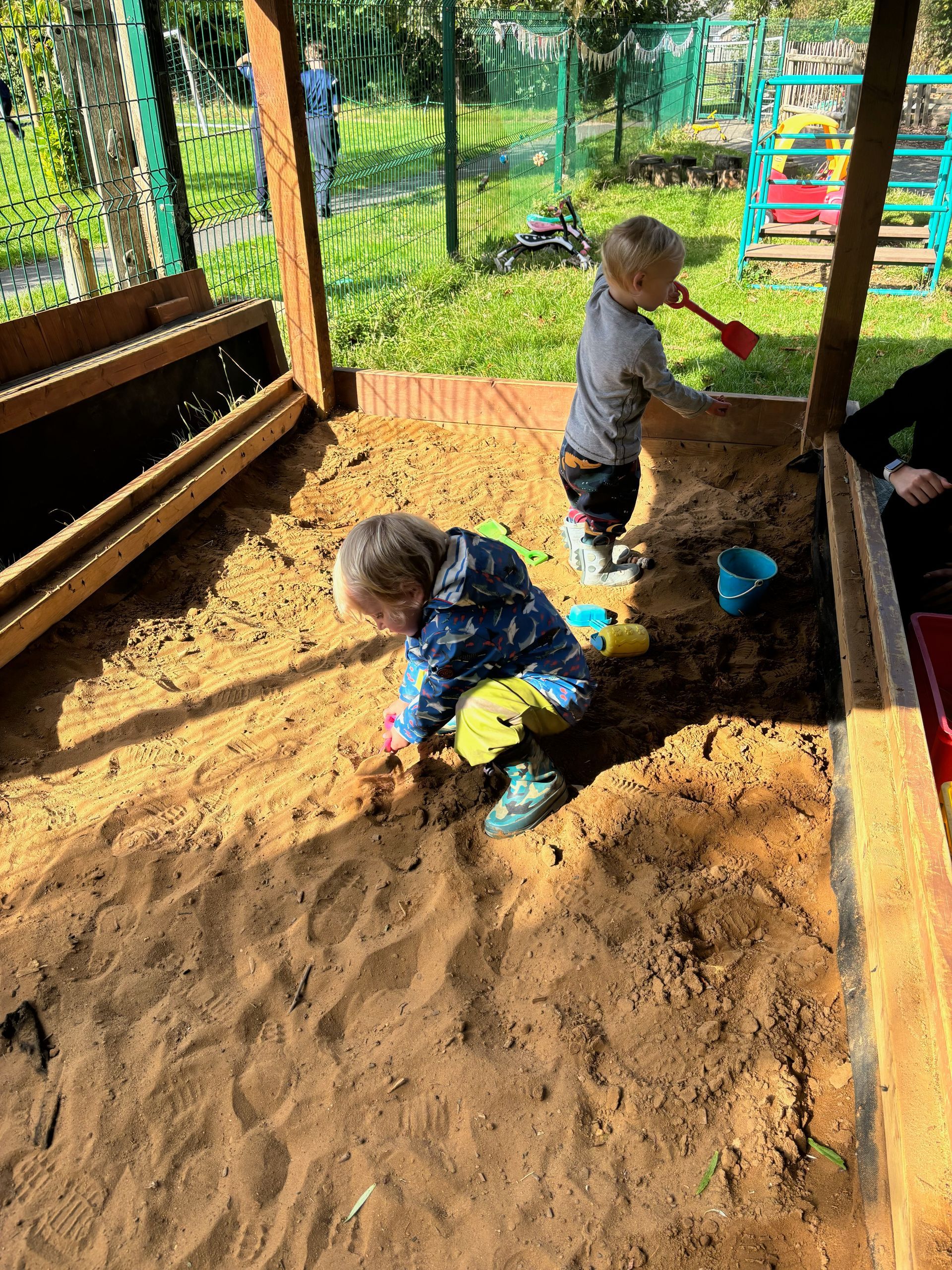 Two young children are playing in a sandbox.