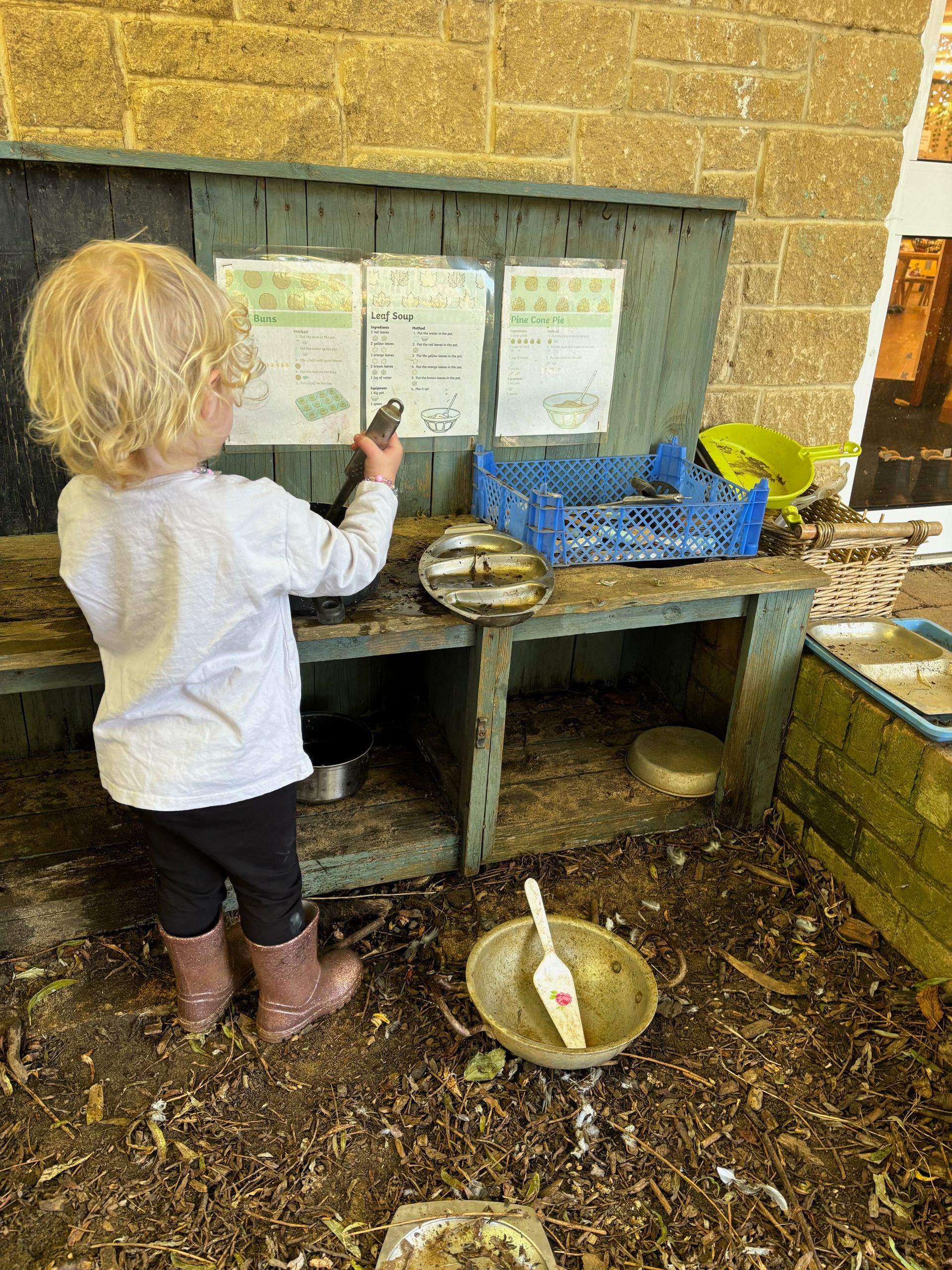 A little girl is playing in the mud in a play area.