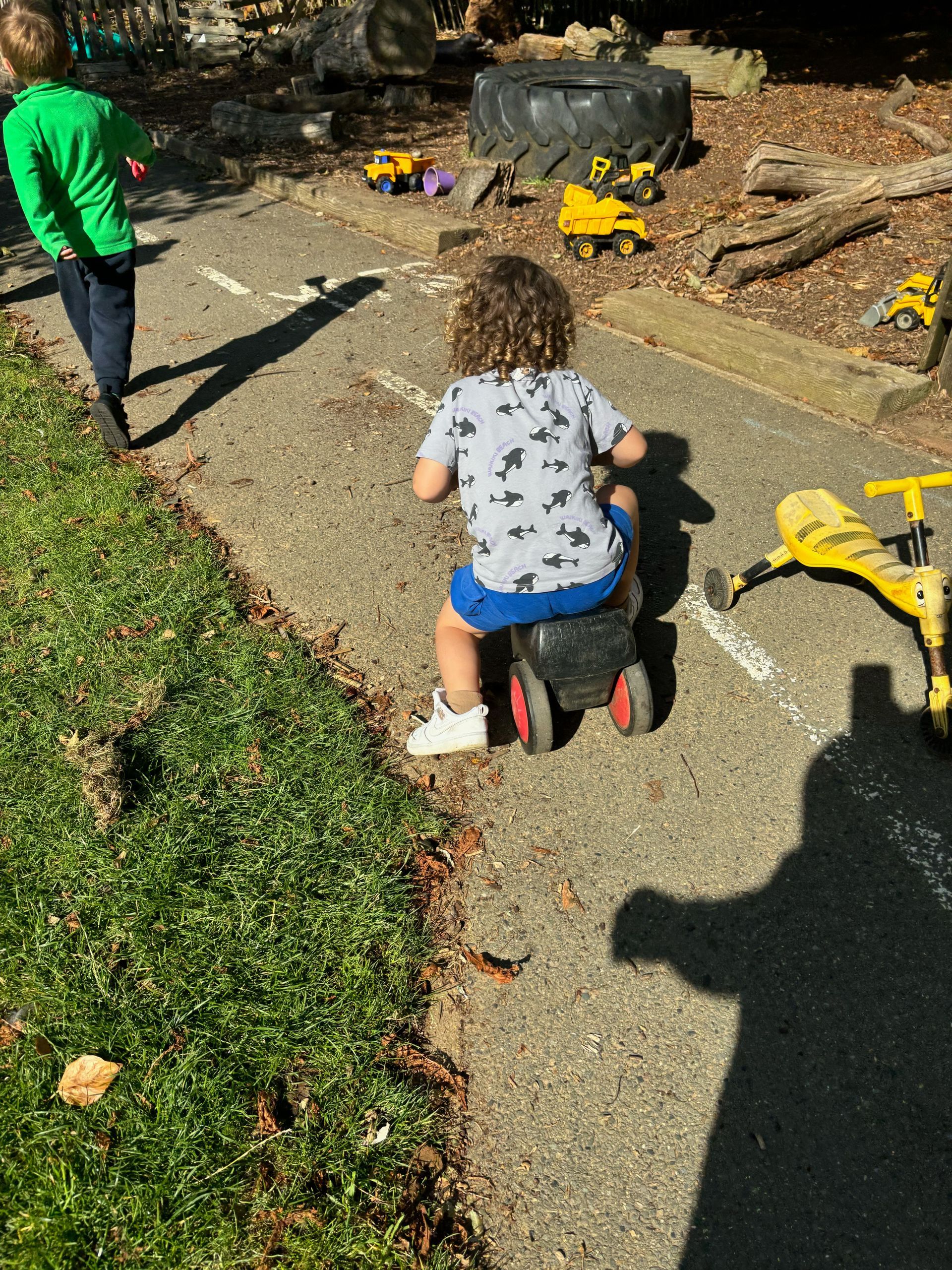 A little girl is riding a toy bike on a sidewalk.