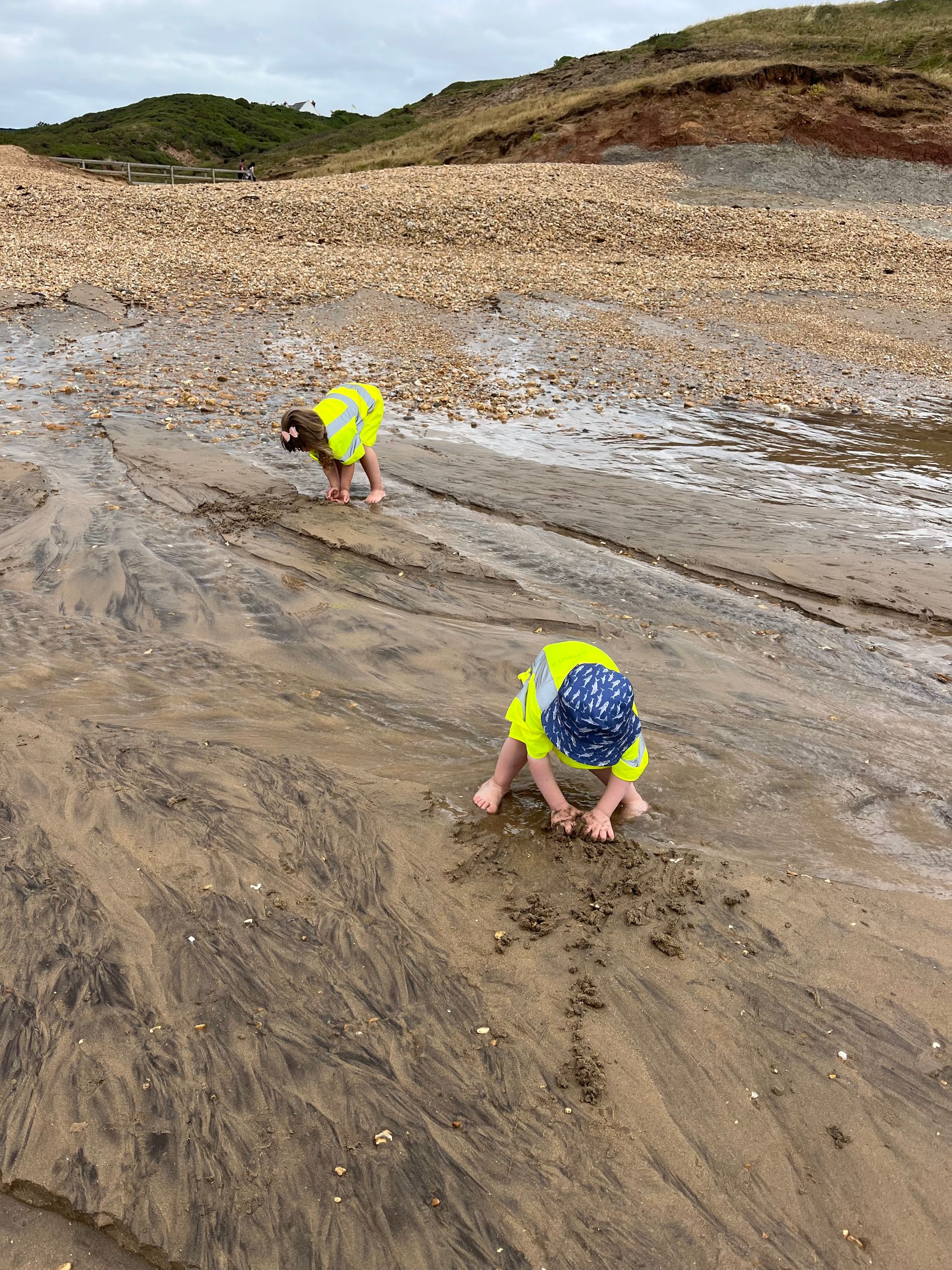 Two children are playing in the sand on a beach.