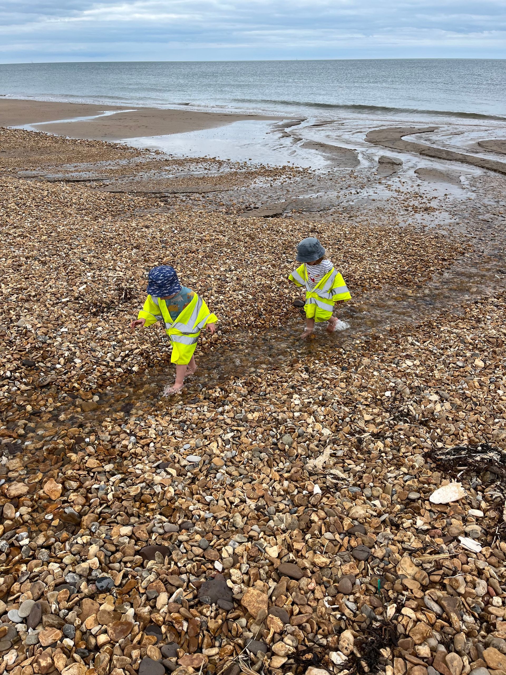 Two children are playing on a rocky beach near the ocean.