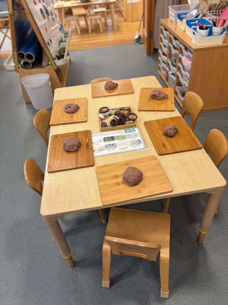 A wooden table with seven cutting boards, each with a round object, and a small stool.