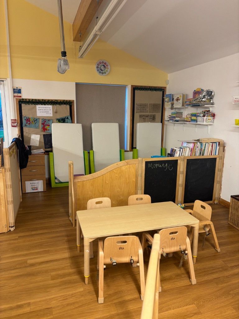 A classroom with a table, chairs, and open cubbies filled with supplies.