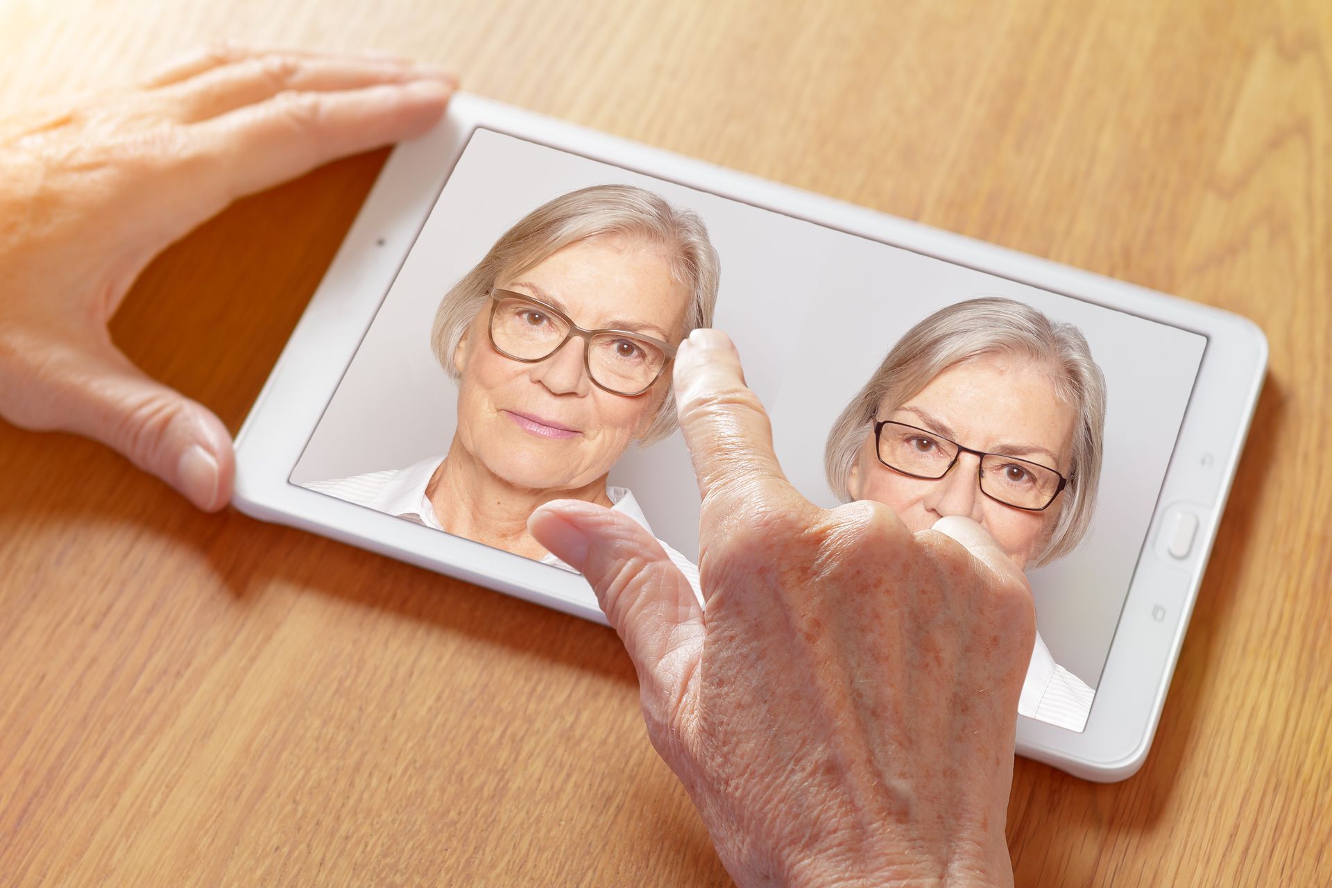 Hands using a smartphone displaying a split-screen portrait during a touch gesture on a wooden table