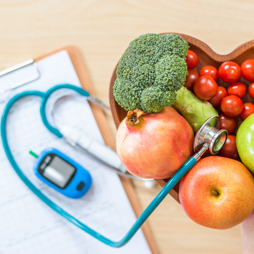 Heart-shaped bowl of fruit and vegetables, stethoscope, glucose meter, clipboard; healthcare, healthy eating.