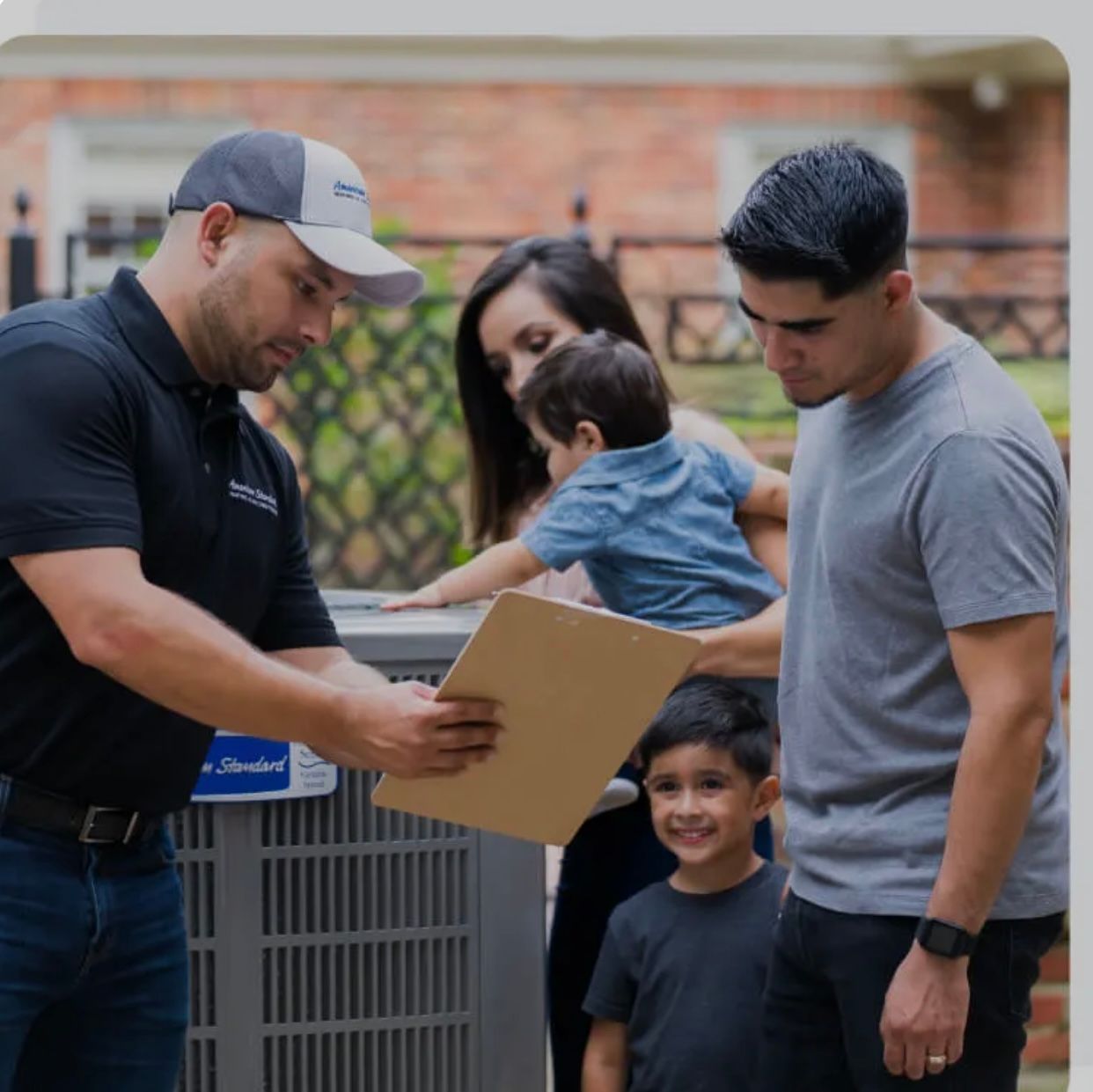 A man in a baseball cap is holding a piece of paper in front of a family 