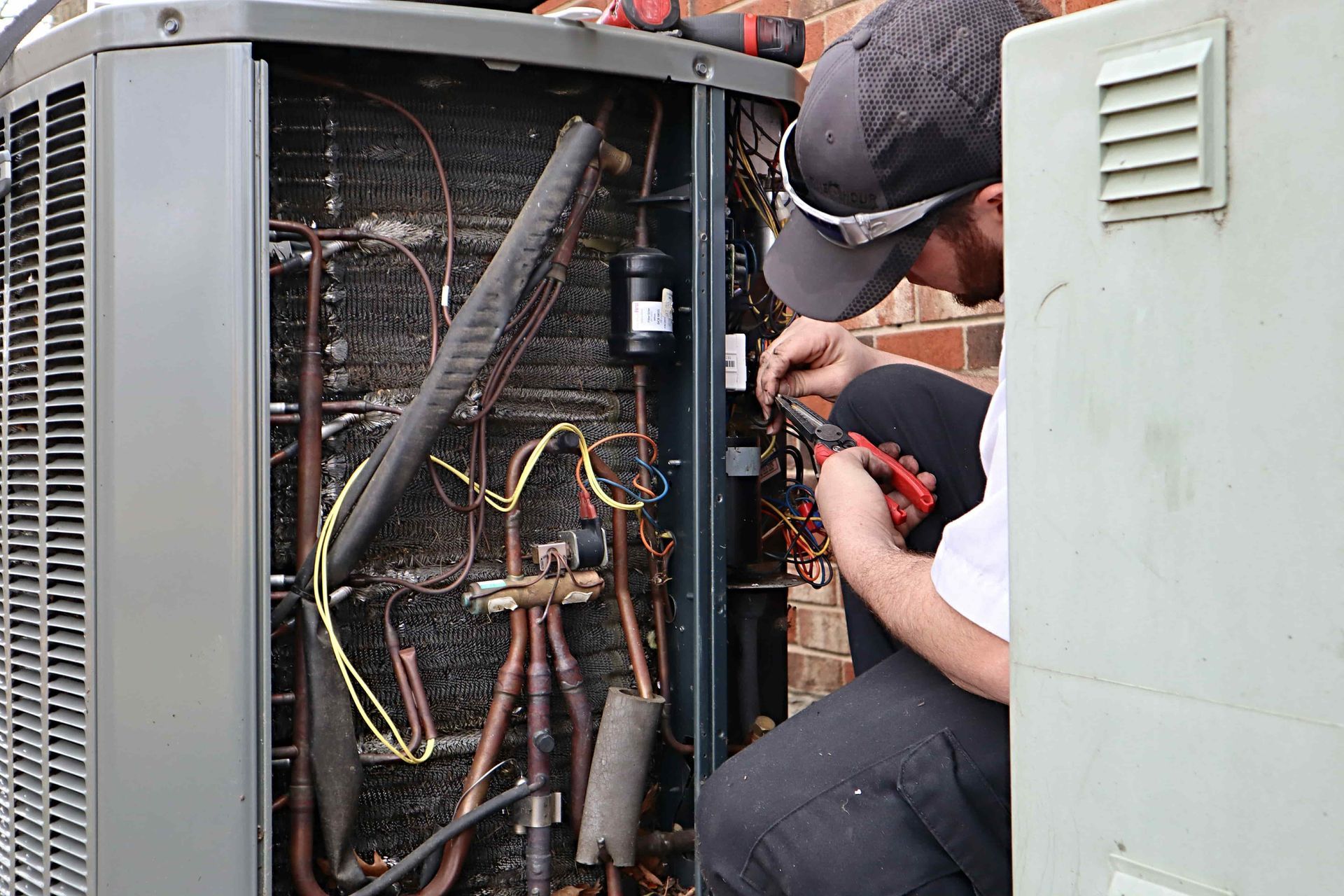 A man is working on an air conditioner outside of a building.