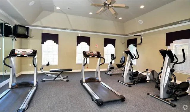 Fitness center with treadmills, elliptical machines, and a weight bench.