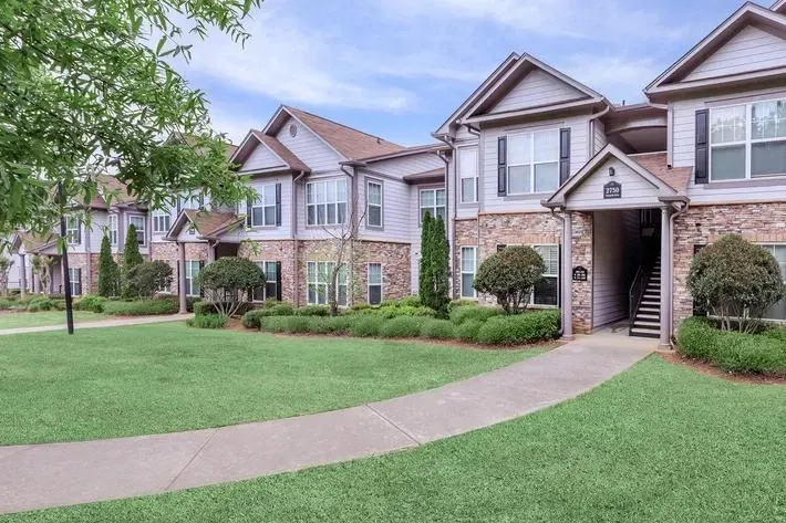 Exterior view of apartment buildings with lush green lawn and trees.