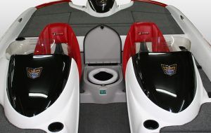 Interior of a white and red motorboat with two black captain's chairs and a marine toilet in the center.