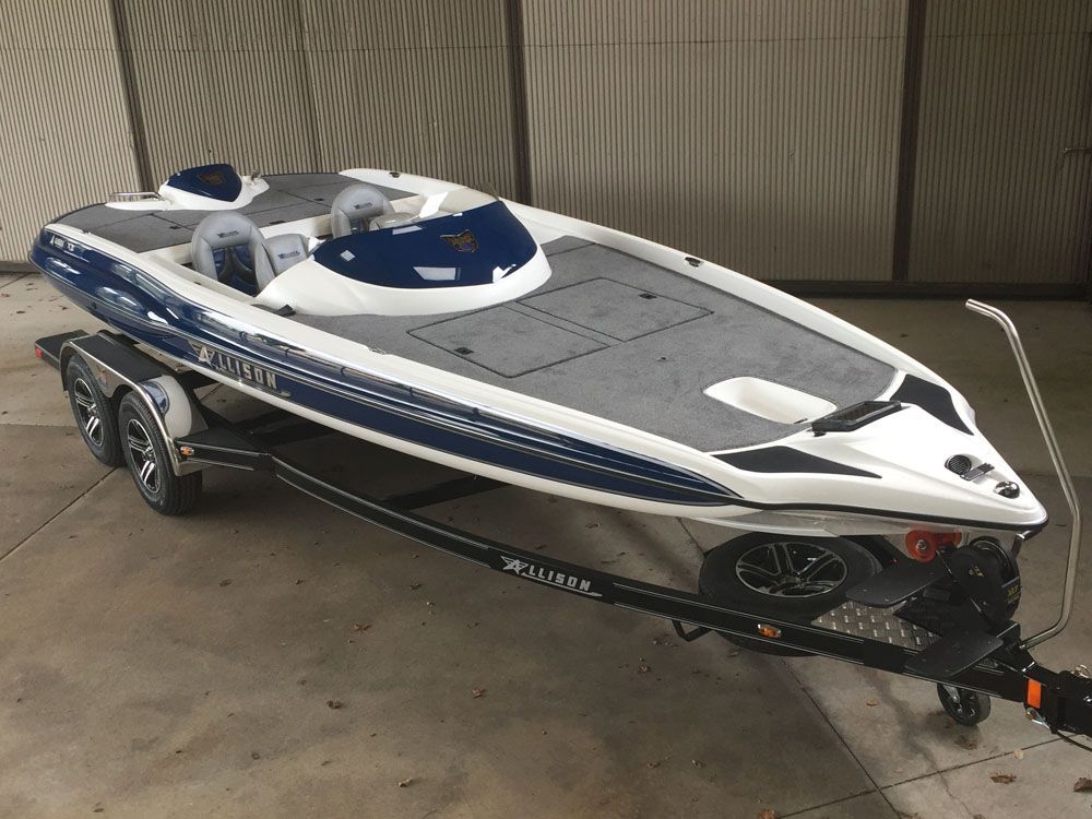 Blue and white motorboat on a trailer. Boat has two seats and a windshield. Trailer is black with shiny wheels.