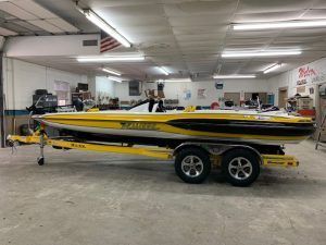 Yellow and black boat on a yellow trailer inside a brightly lit garage.