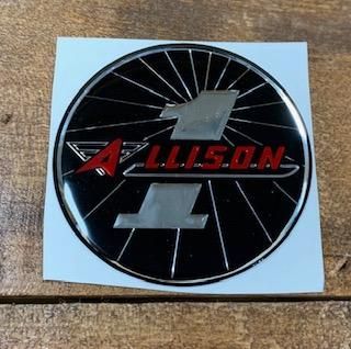 Allison logo, black circle with chrome accents, red