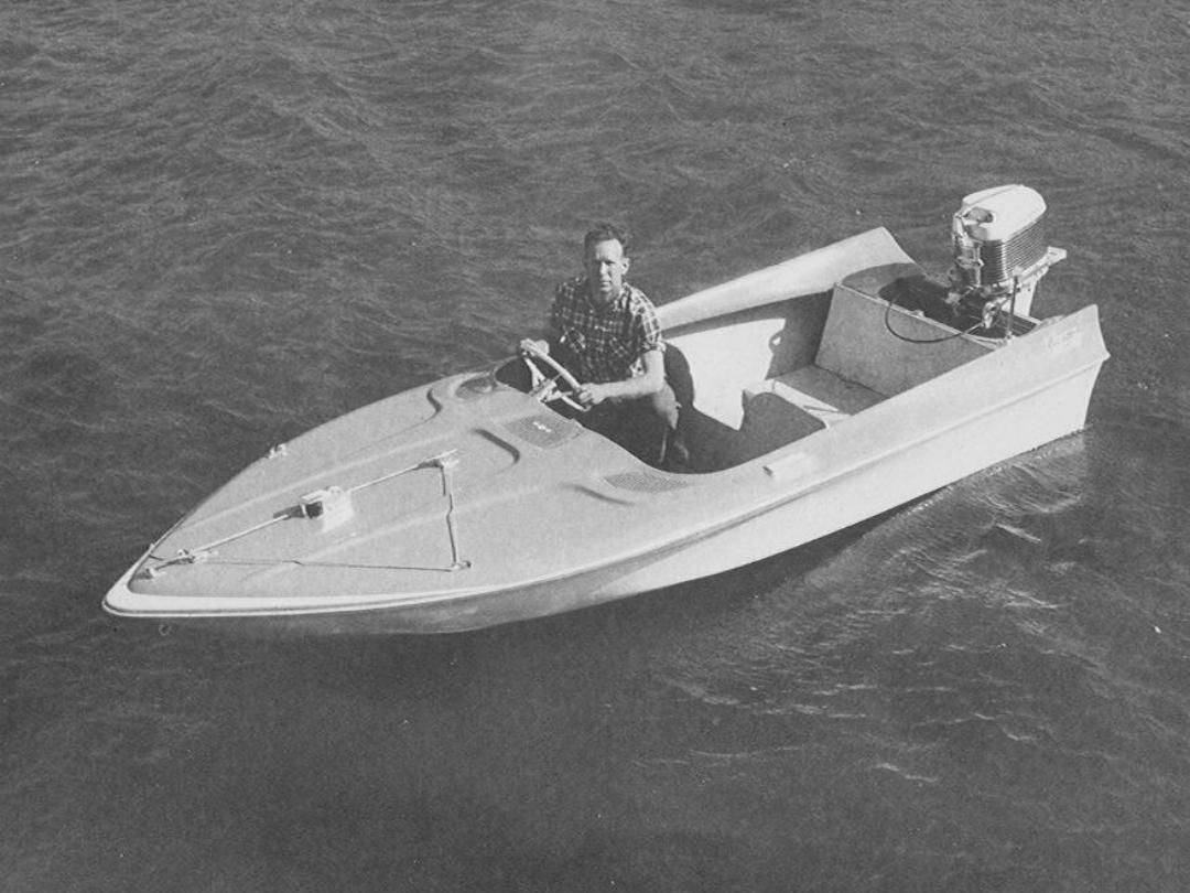 Man sits inbass boatt on water, operating an outboard motor.