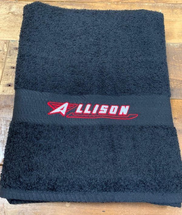 Black towel folded, with "ALLISON" embroidered in red and white.