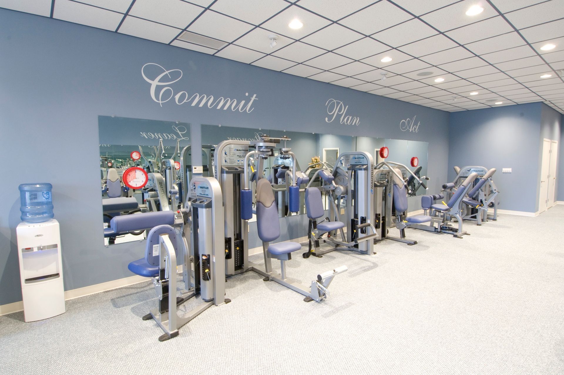 Bright gym with blue and silver exercise machines on a white floor