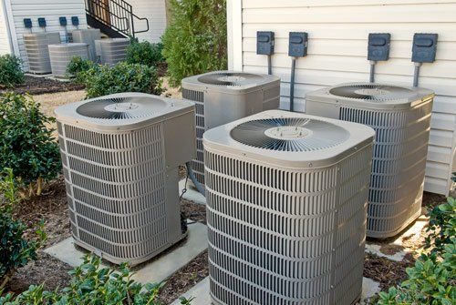 A row of air conditioners are sitting outside of a building.