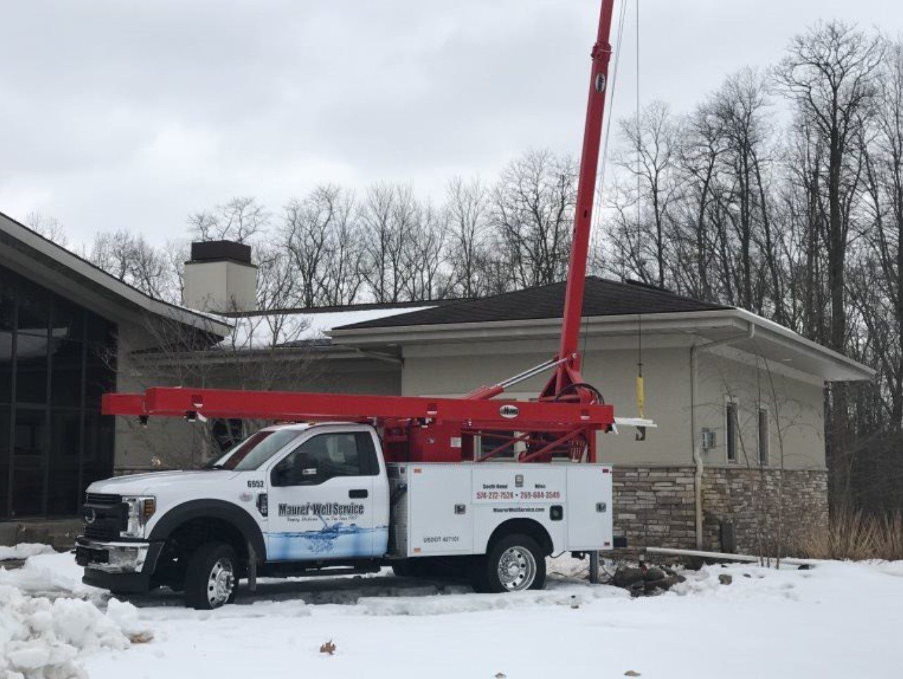 Septic tank pumping truck with hoses and equipment for waste removal on grassy site.