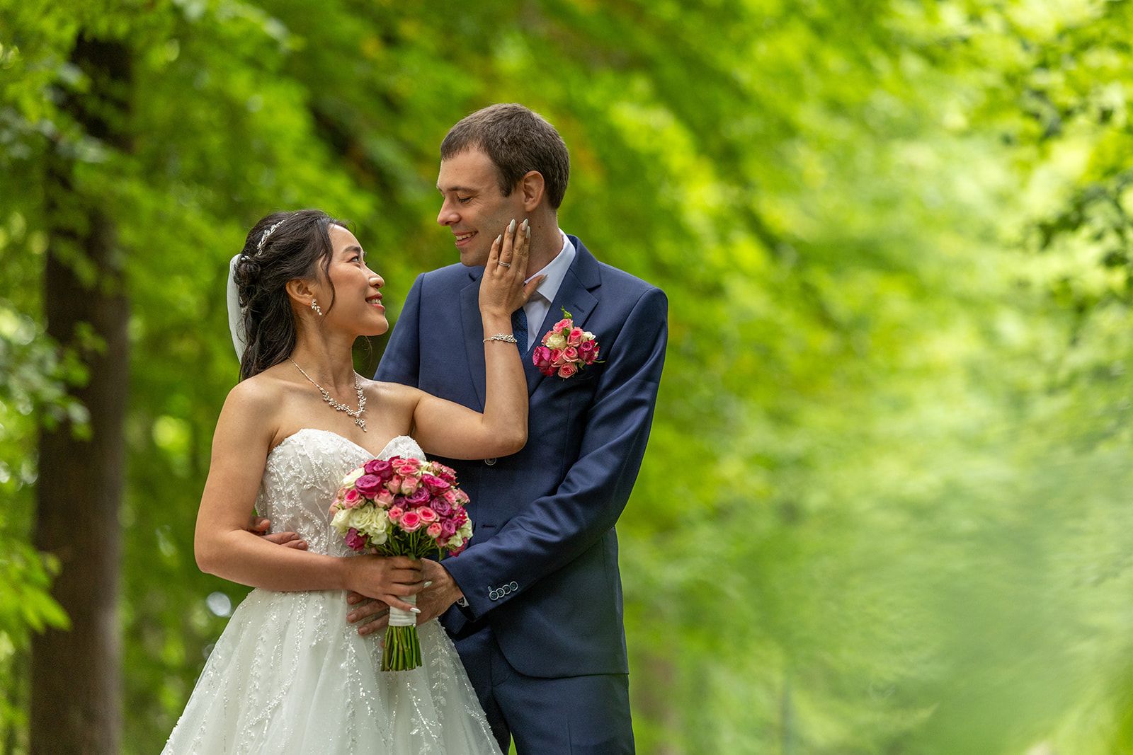 Pasgetrouwden lopen hand in hand door het hoge gras. De vrouw draagt ​​een witte jurk. De man een pak. Ze glimlachen.