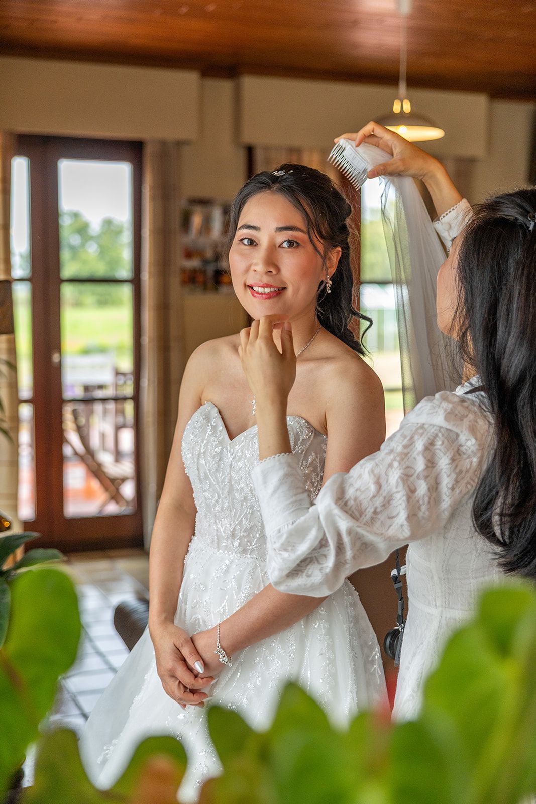 Een stel omhelst elkaar op het strand; de vrouw in de witte jurk houdt een boeket vast, de man in het beige pak raakt haar gezicht aan, met de oceaan op de achtergrond.