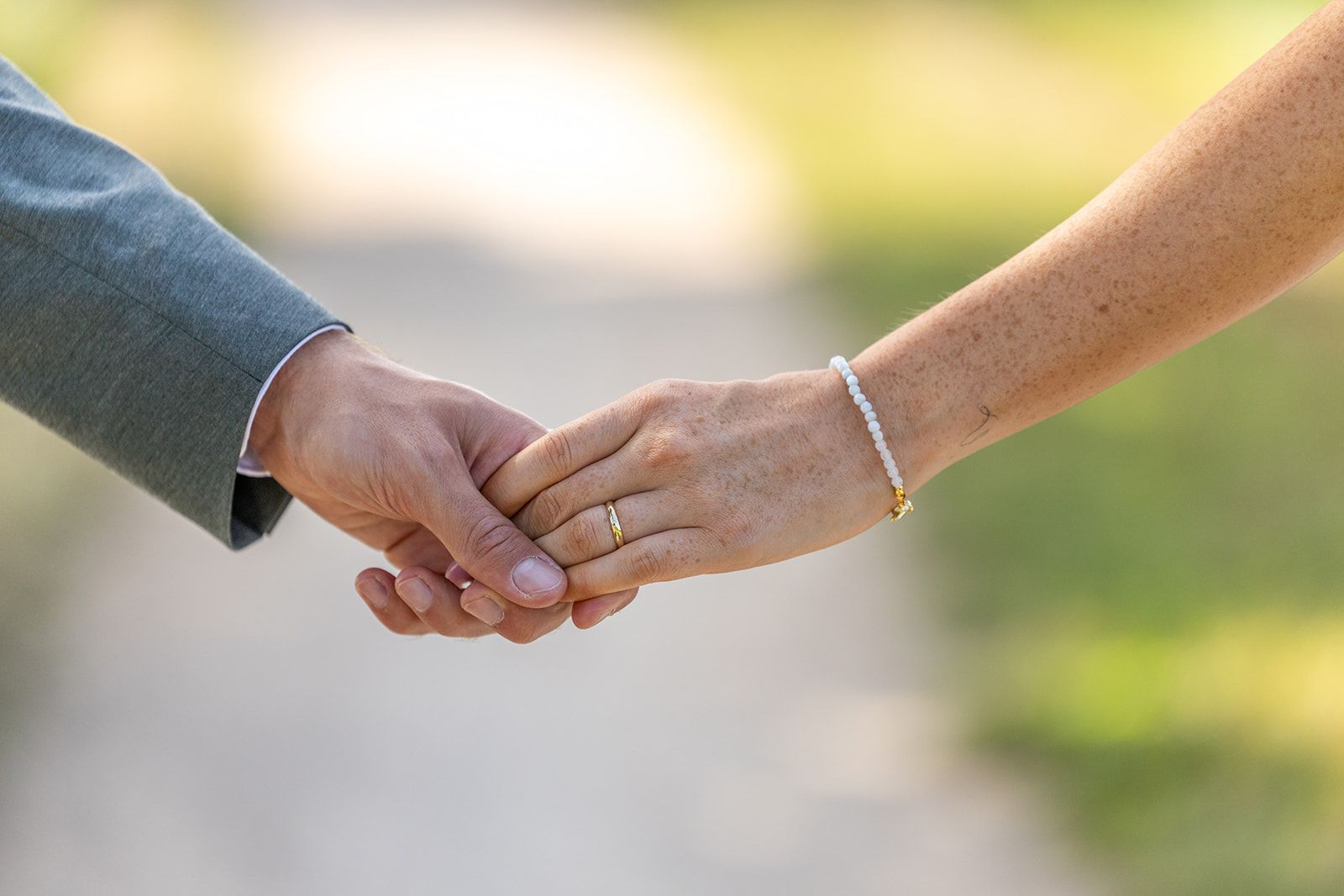 Man en vrouw houden elkaars hand vast; een trouwring is zichtbaar.