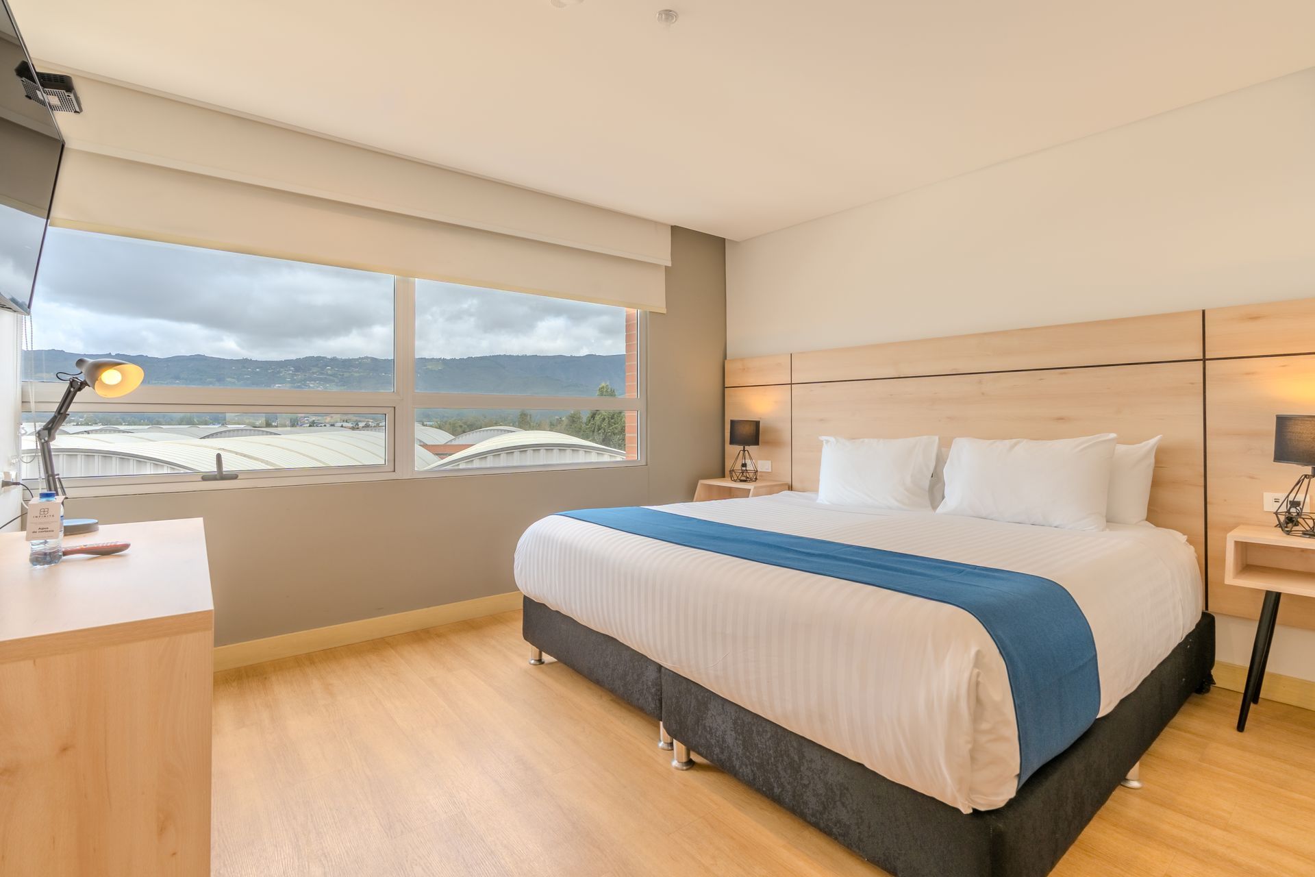 Una habitación de hotel con una cama grande y un televisor de pantalla plana.