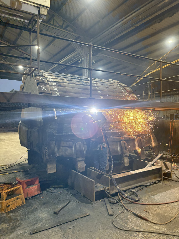 Sparks fly as a large metal object is being cut with a torch inside a factory— North Queensland Hard Facing (NQHF) In Fredericksfield, QLD