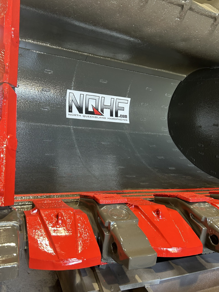 Inside of machinery. Red and gray painted parts with a white logo on the gray wall— North Queensland Hard Facing (NQHF) In Fredericksfield, QLD