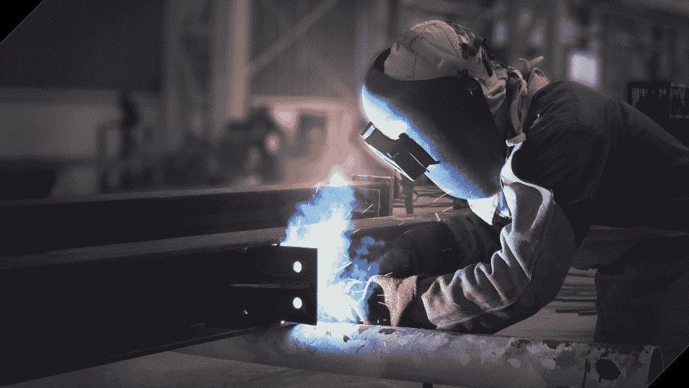 A Man is Welding a Piece of Metal in a Factory — North Queensland Hard Facing (NQHF) In Fredericksfield, QLD