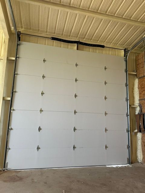 White garage door closed, with brown metal frame and cream-colored ceiling, indoors.