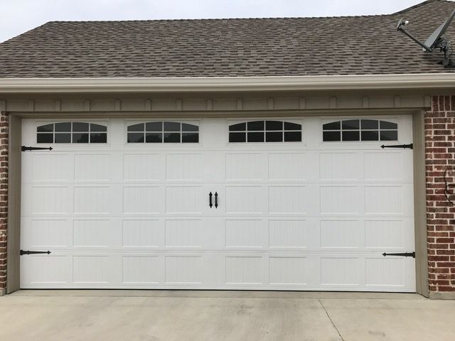 White garage door with four arched window panes, black hardware, and brick detailing.