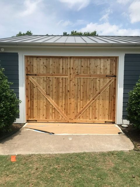 Wooden garage doors with diagonal supports on a blue building.