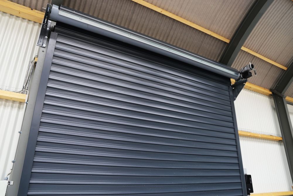 Dark gray rolling shutter door, closed, in a warehouse setting.