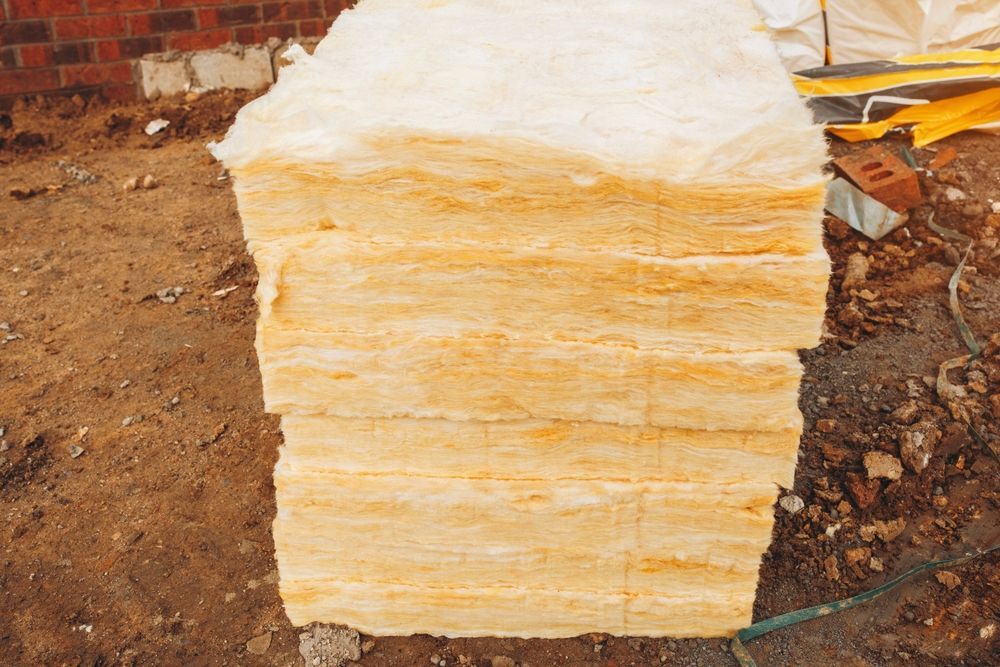 Stack of rectangular yellow insulation material on a construction site.