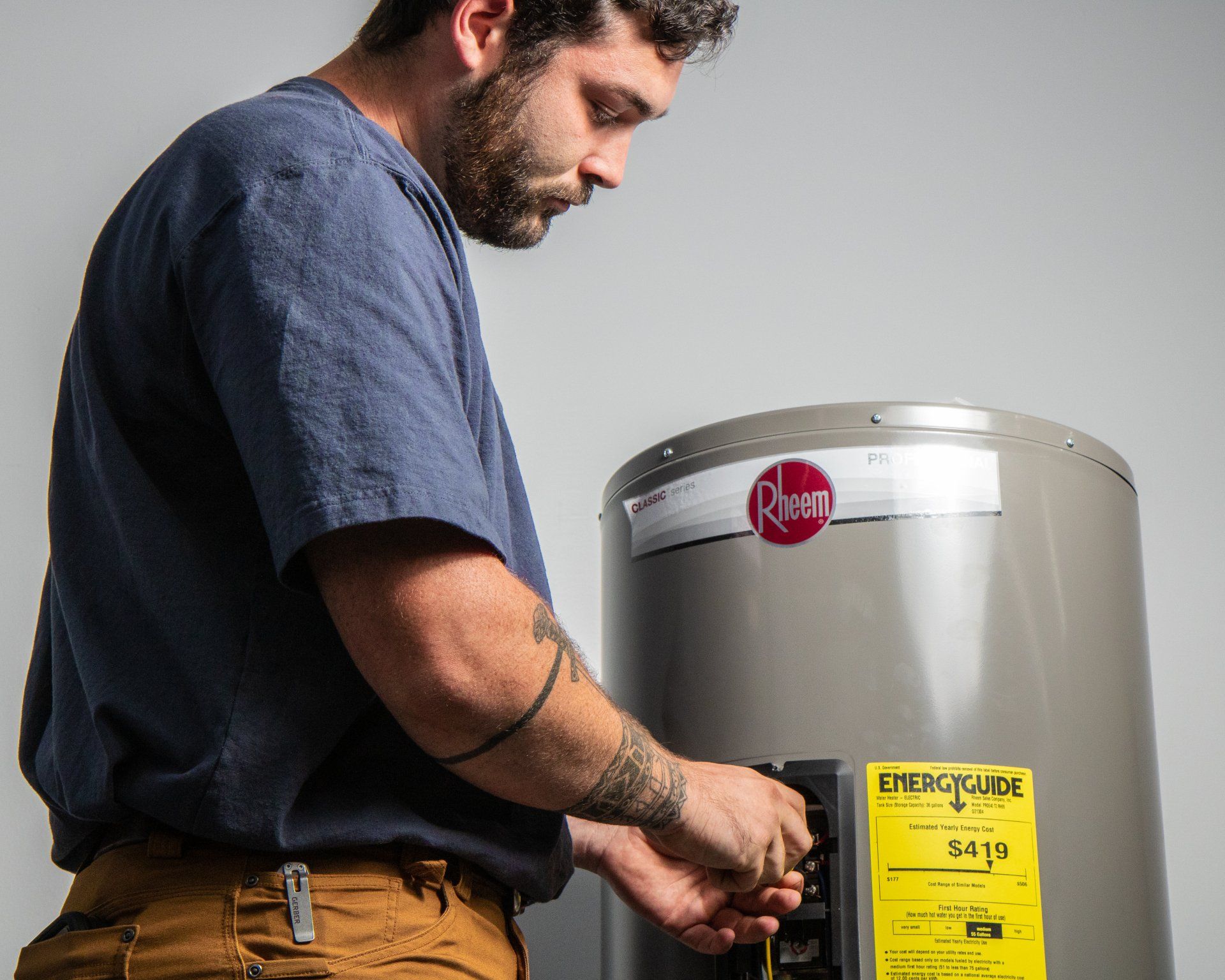 Technician unscrewing thermostat on an electric water heater