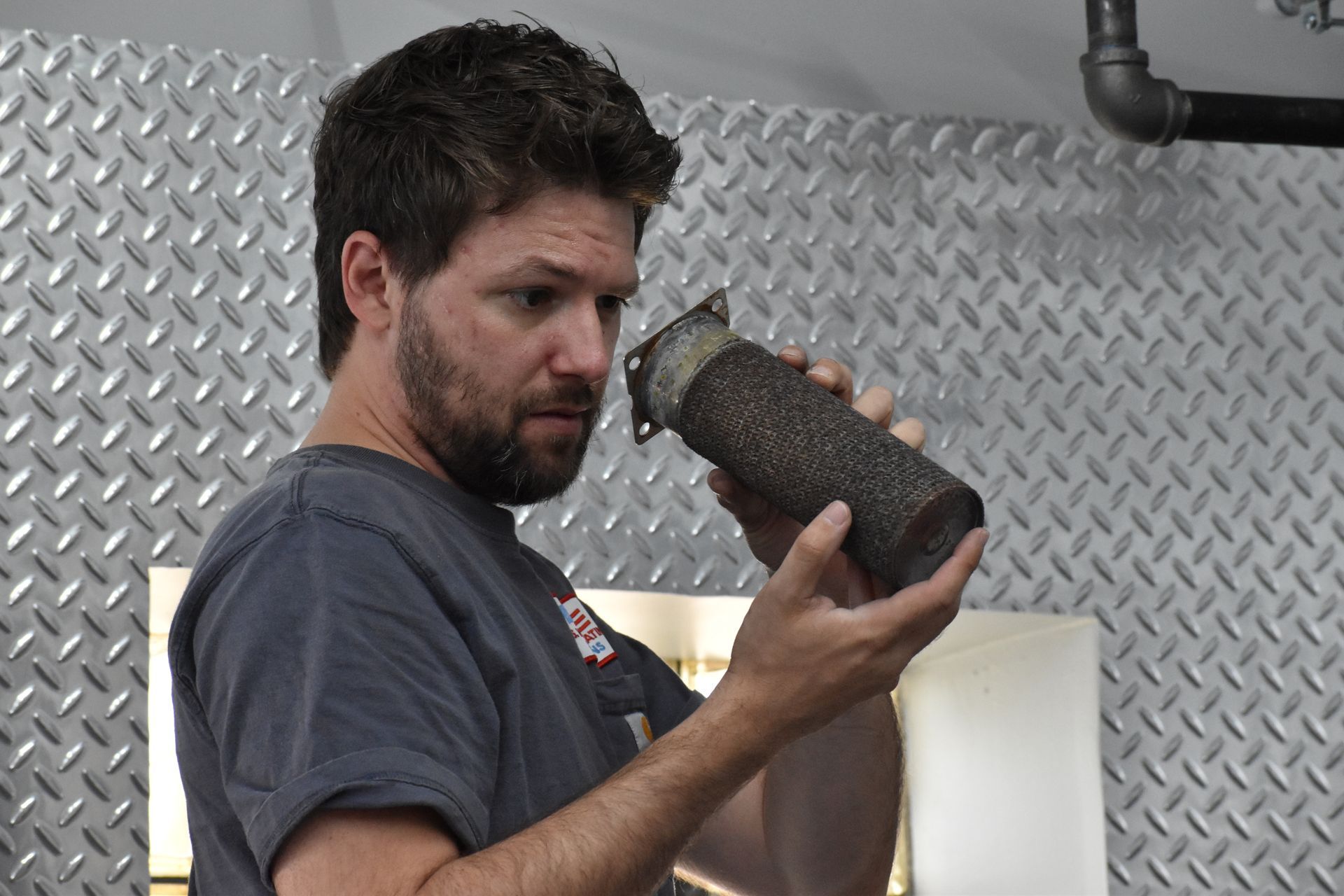 Technician inspecting a burner tube on a commercial water heater during annual maintenance service