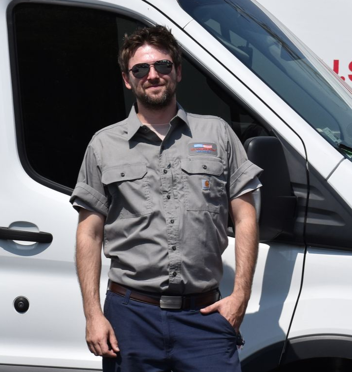Water heater service technician standing next to his U.S. Water Heating Solutions service truck