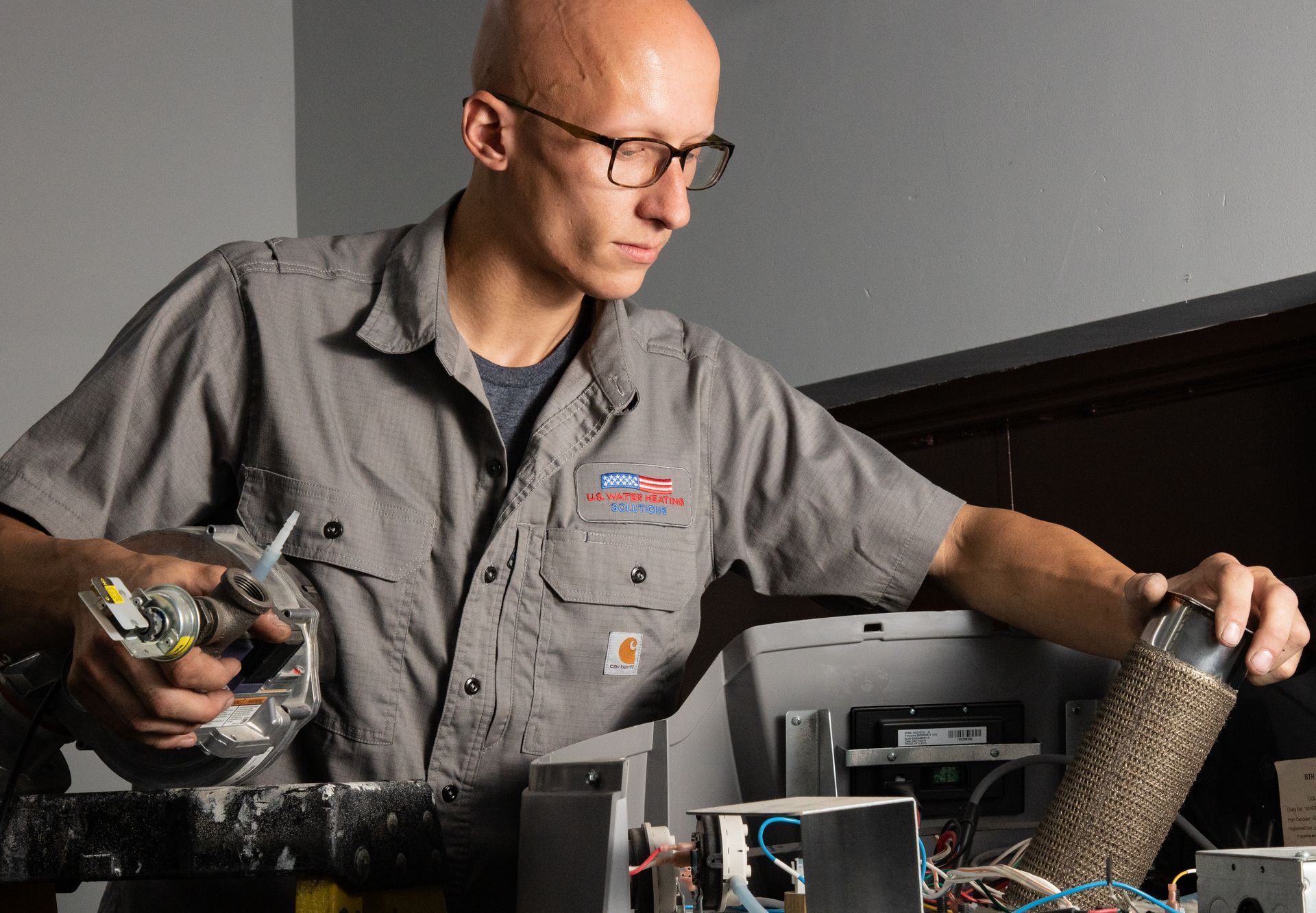 Technician removing blower and burner assembly from commercial water heater