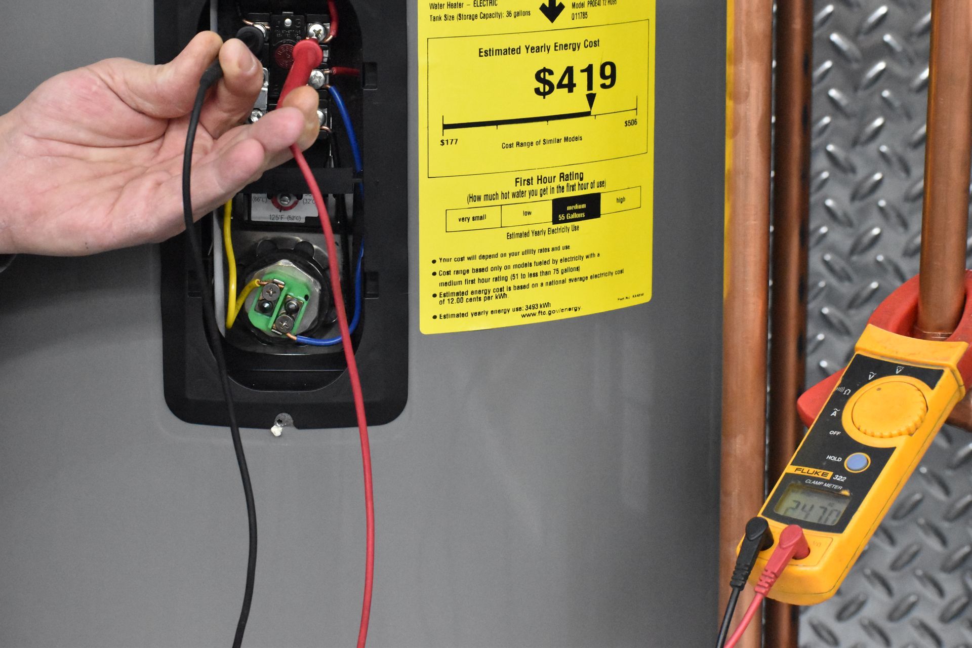 Technician taking voltage readings on upper thermostat to diagnose electric water heater issue