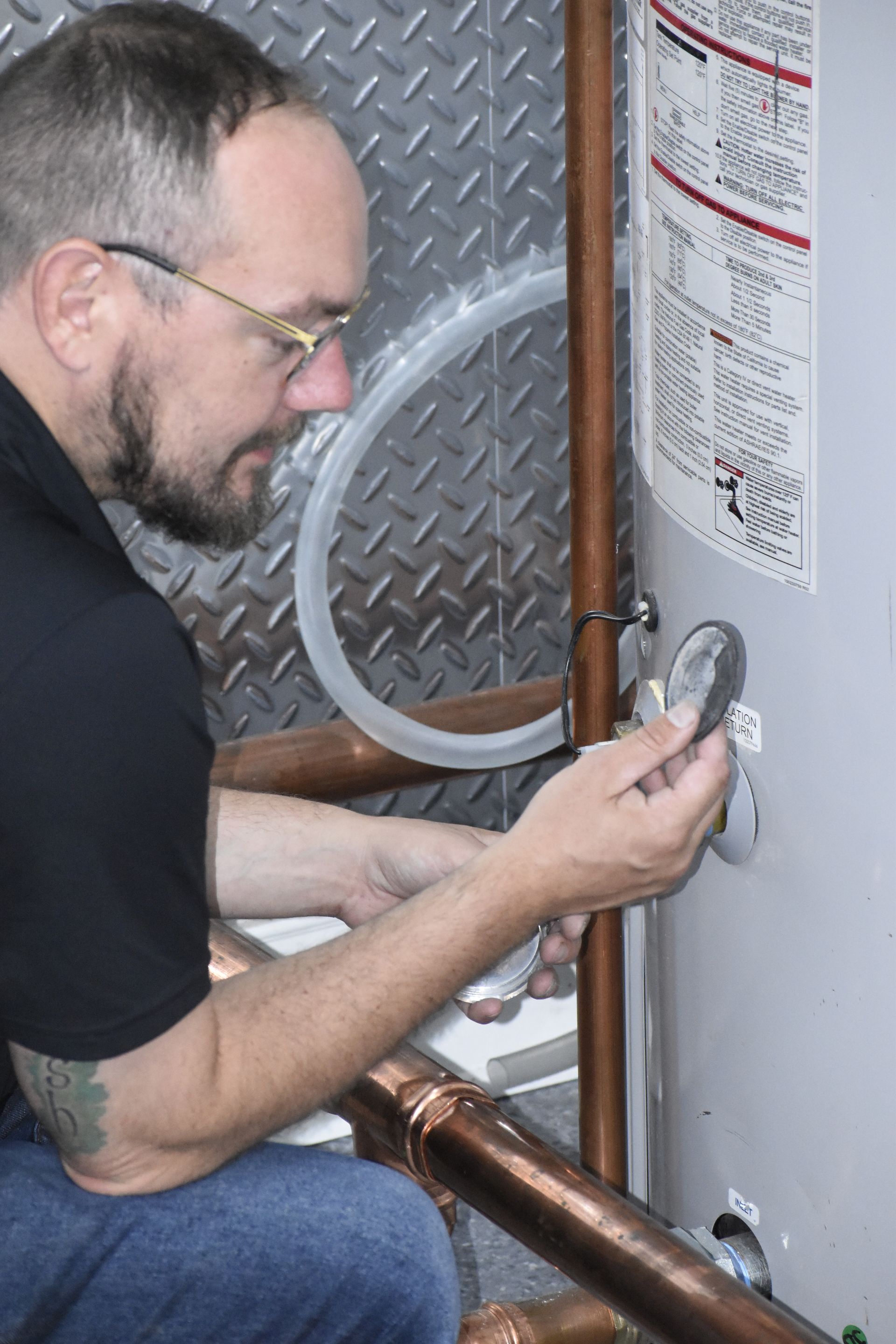 Technician performing water heater maintenance, inspecting condensate trap gasket