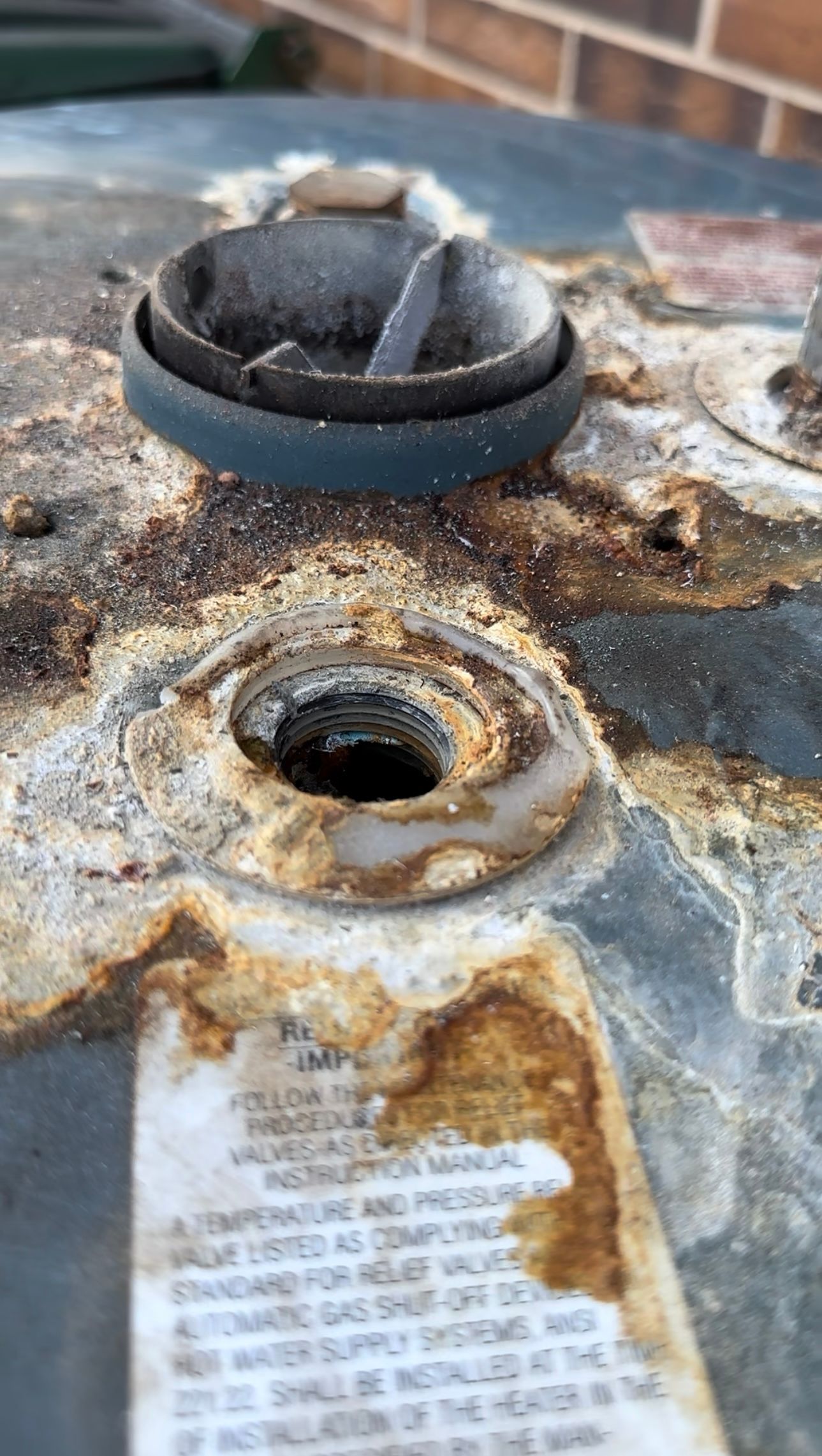 Top of water heater showing severe signs of aging with rust, dirt, and water marks
