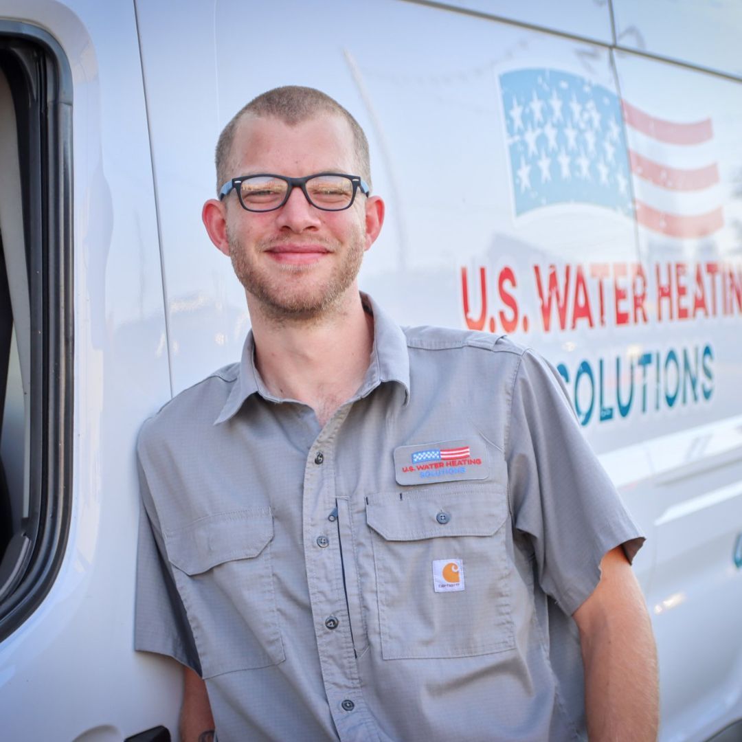 Water heater repair technician, plumbing standing next to his U.S. Water Heating Solutions truck