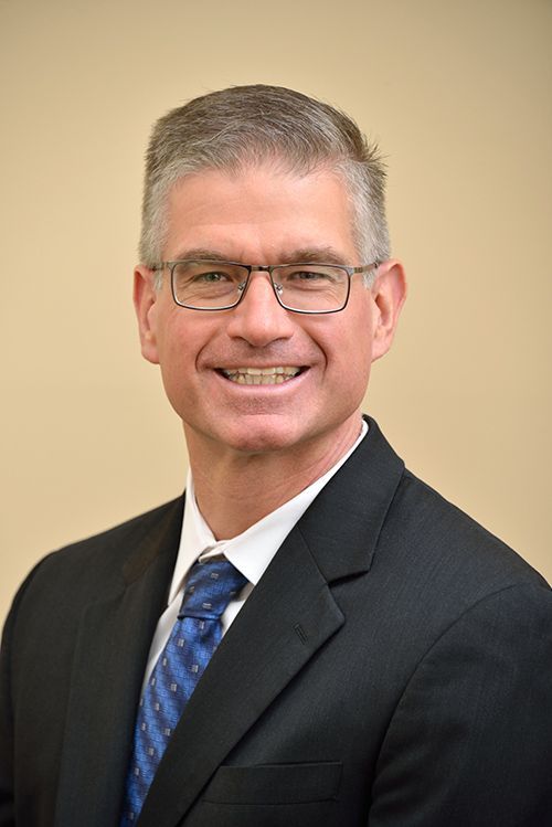 a man (Dr. Lieb) in a suit and tie is smiling for the camera