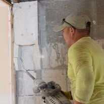 Worker using a power tool on a wall during interior construction