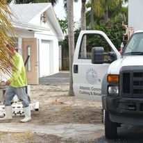 Worker in neon vest outside a white house near a utility truck with an open door