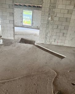 Unfinished concrete room with cinderblock walls, a window, and a trench in the floor.