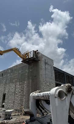 Construction site with excavators working on a tall concrete building under a cloudy sky