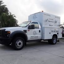 White utility truck parked on pavement with company signage on the side and rear.
